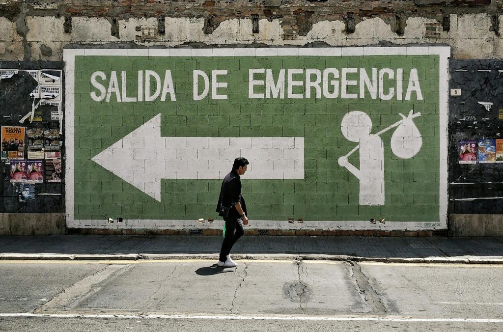 A man walks by an emergency exit graffiti mural on a street in Málaga, Spain.