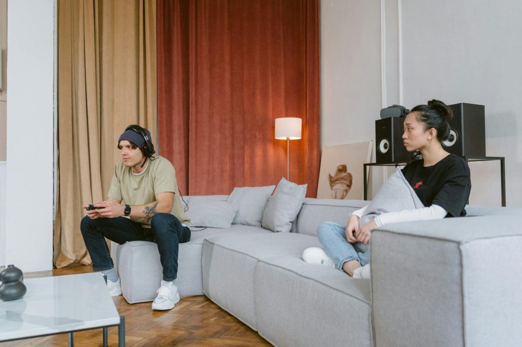 A young couple engaged in gaming and relaxation in a modern living room setting, showcasing leisure and technology.