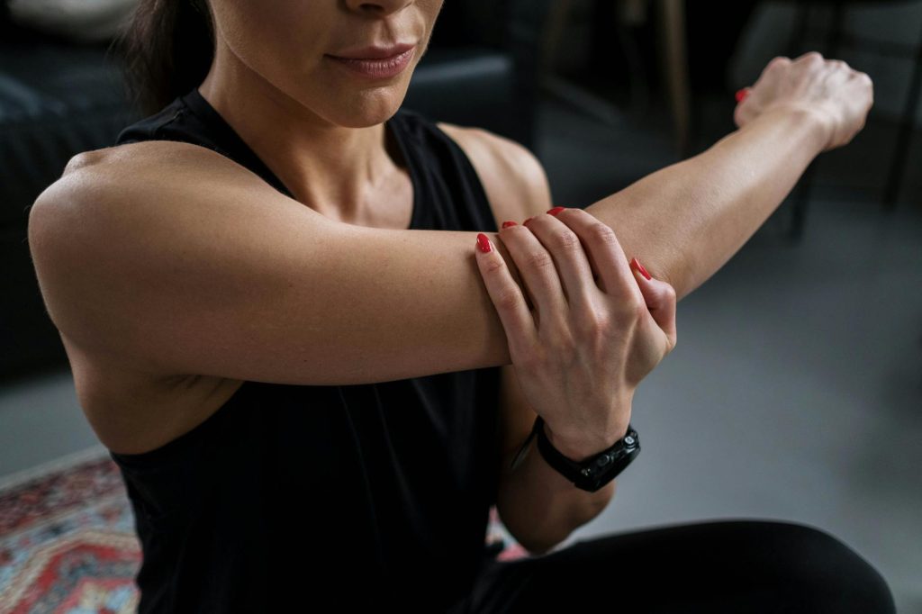 Close-up of a woman stretching her arm indoors during a fitness routine.