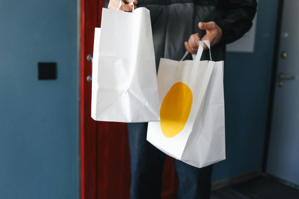 Close-up of hands holding paper shopping bags indoors.