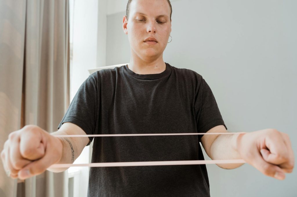 Man exercising with a resistance band indoors, promoting home fitness and wellness.